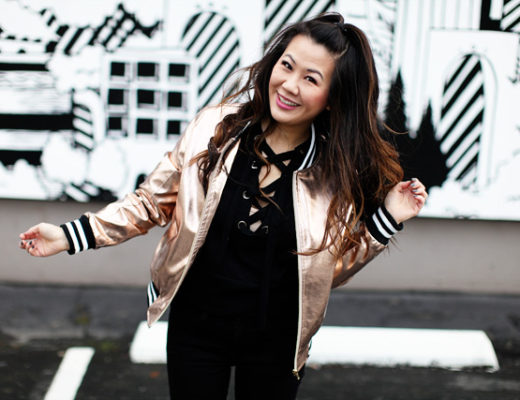 girl wearing bomber jacket in front of wall