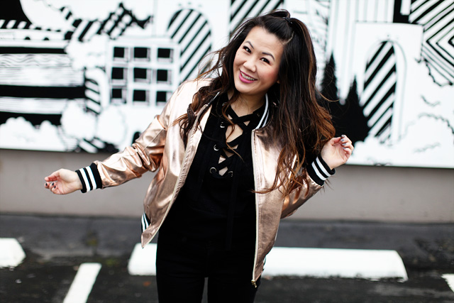 girl wearing bomber jacket in front of wall